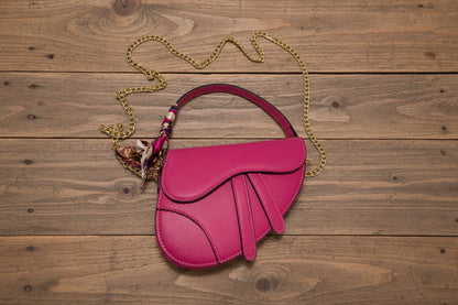 Pink handbag with a gold chain on a wooden background