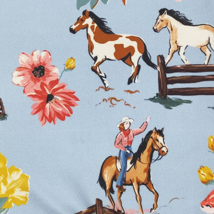 Fabric pattern with horses, a cowgirl, and flowers on a blue background