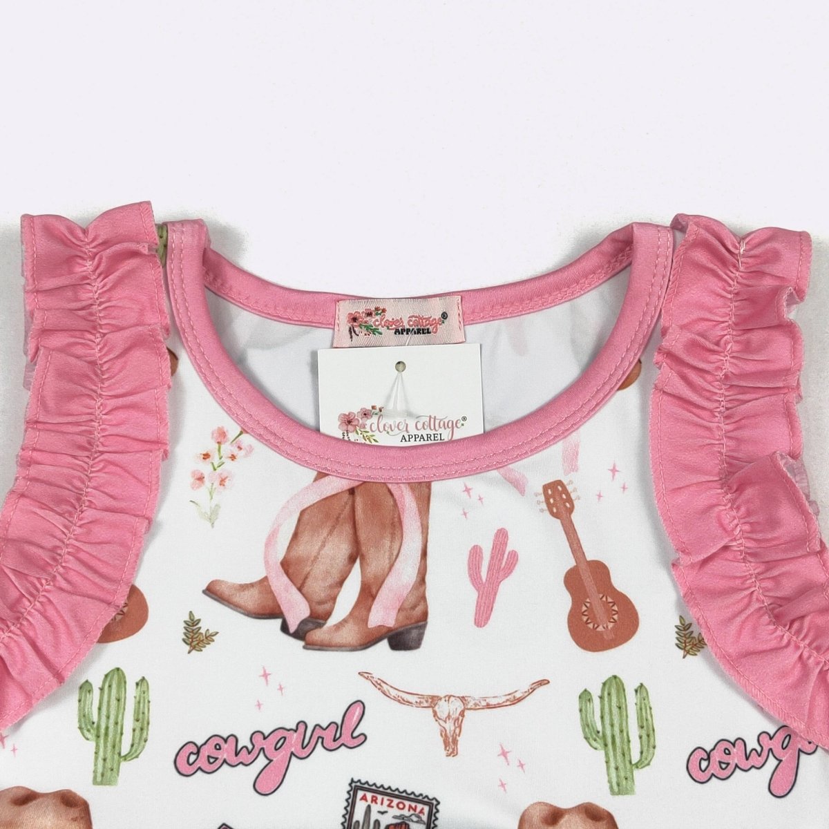 Pink toddler outfit with ruffled details on a white background featuring cowboy graphics.