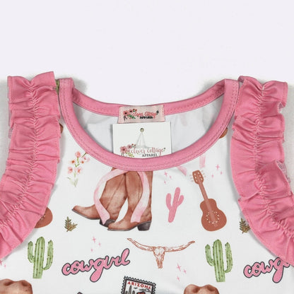Pink toddler outfit with ruffled details on a white background featuring cowboy graphics.