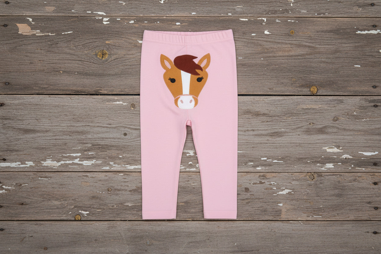 Pink pants with a horse design on a barnwood background