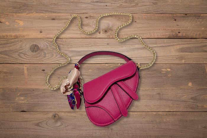 Pink handbag with a gold chain on a wooden background