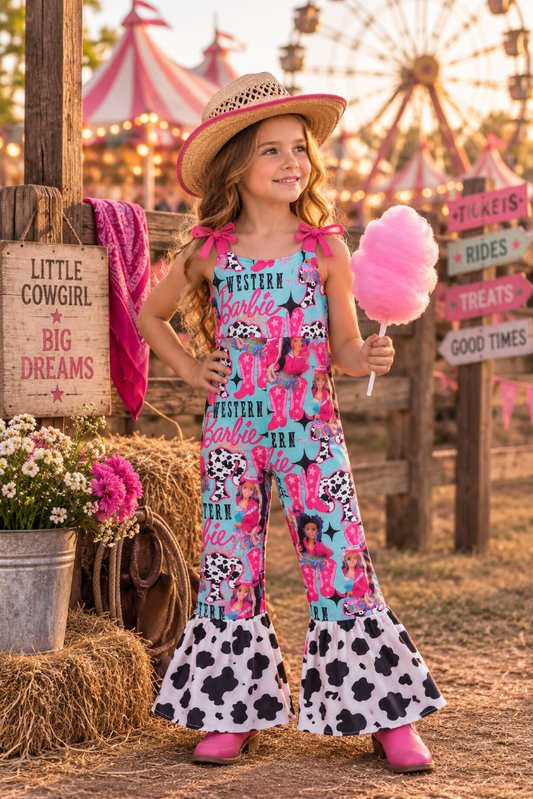 A young girl stands in a rustic fair or carnival setting wearing a bright pink and turquoise Western Barbie-themed jumpsuit with cow-print flared hems, a straw hat, and holding a pink cotton candy. The background features wooden signs, hay bales, and a blurred ferris wheel.