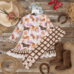 Floral dress with horse pattern, cowboy boots, and rustic accessories on a wooden surface
