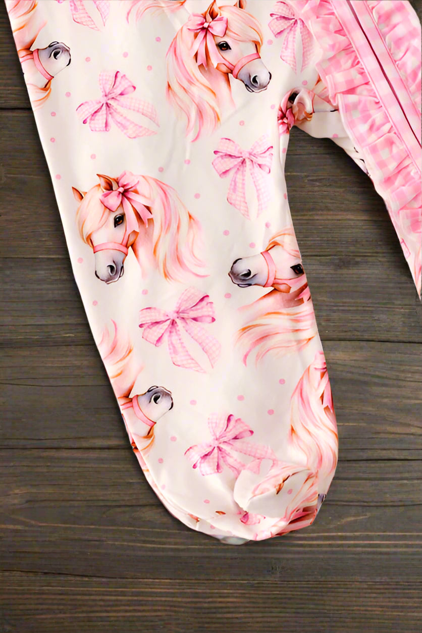 Baby romper footsie with pink horse and bow pattern on dark wood surface
