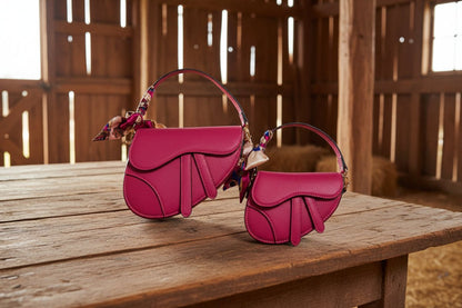 Two pink handbags with a matching scarf on a barn background