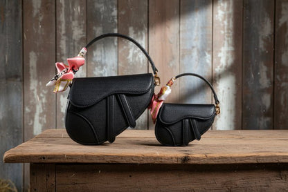 Black handbag with pink floral accents on a wooden background