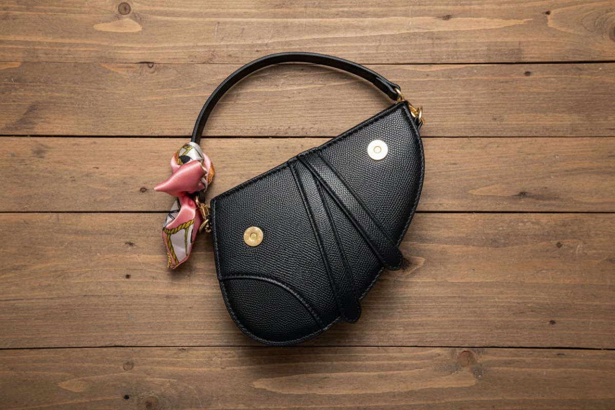 Black handbag with decorative elements on a wooden background