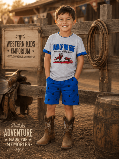 Young boy in cowboy attire standing in front of a wooden fence with a sign that reads 'Western Kids Emporium'.