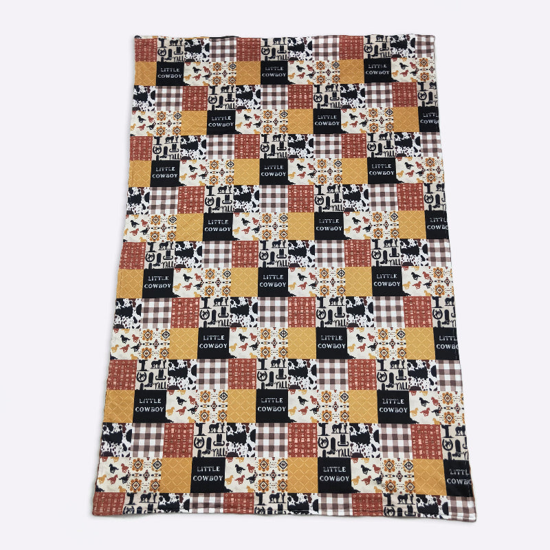 Patchwork blanket with 'Little Cowboy' text and plaid patterns on a white background