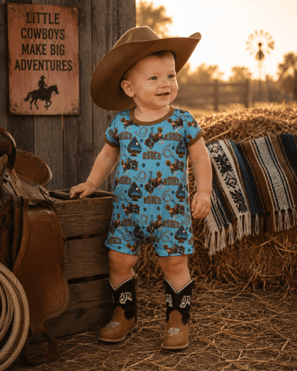 Child in cowboy rodeo outfit with boots and hat standing in a rustic setting with a sign and hay bales.