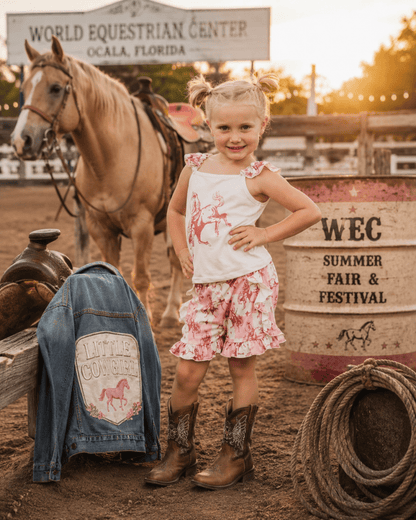 Young girl in a cowgirl short set standing next to a horse at the World Equestrian Center in Ocala, Florida.