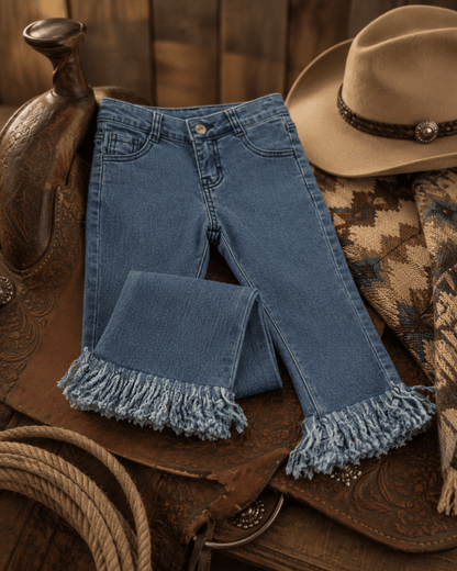 Blue jeans with fringe on a rustic horse saddle with a cowboy hat and lasso.