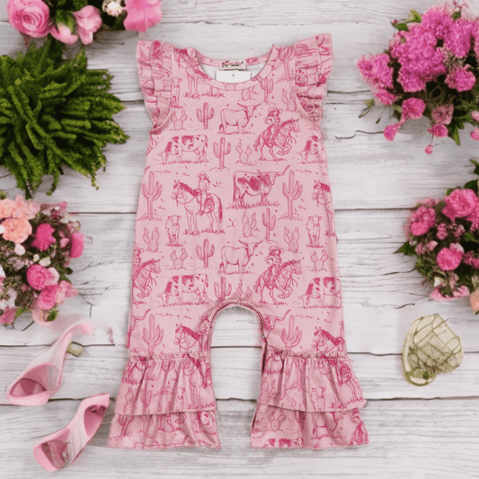 Pink romper with cowboy pattern on a wooden surface with flowers 