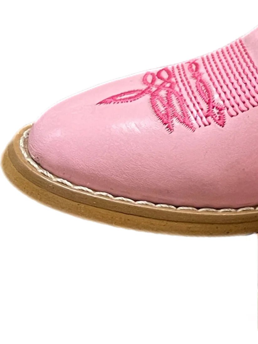 Close-up of a pink children's boot with a brown sole on a white background