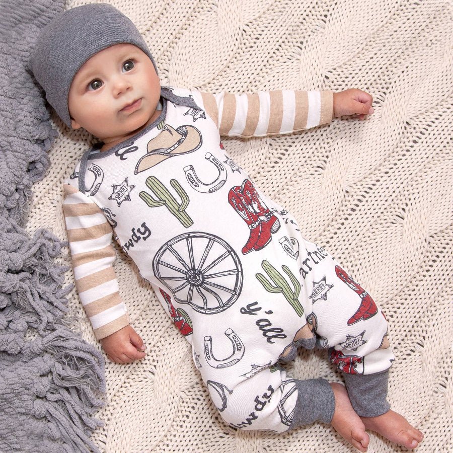 Baby wearing a romper with cowboy print on a textured blanket