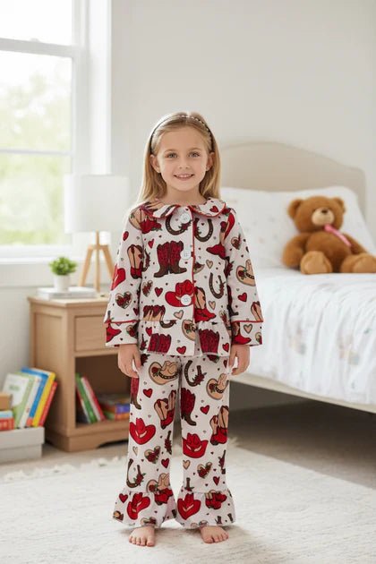 Child wearing a red and white pajama set with animal patterns in a bedroom.