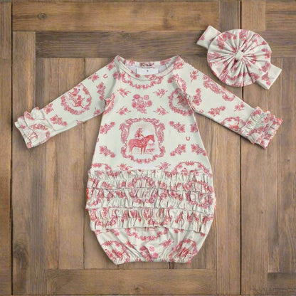 Baby romper with pink floral and horse pattern and matching headband on a wooden board background