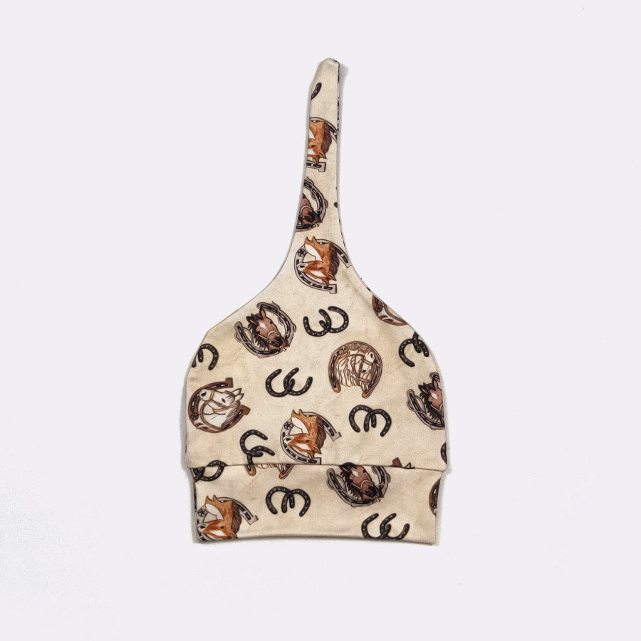 A beige fabric dust bag featuring an all-over print of brown and black horseshoes, photographed flat against a light gray background.