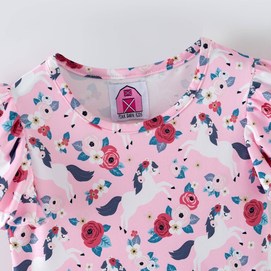Pink children's outfit with pony and floral pattern on a white background