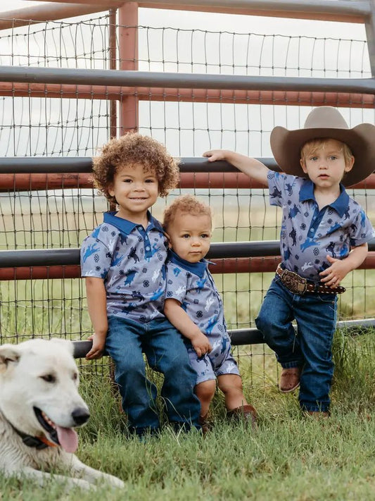 Three boys in cowboy polo shirts by red fence
