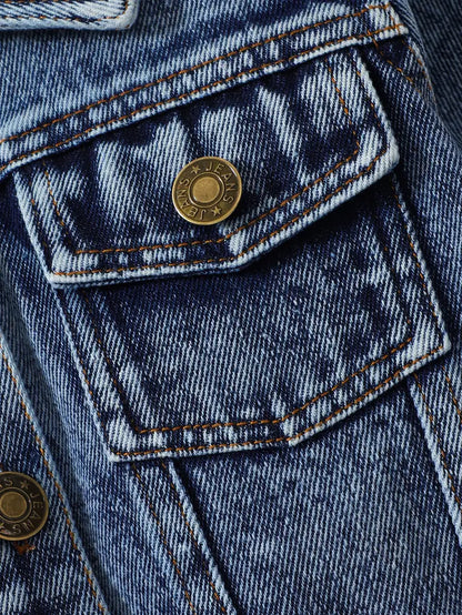 Close-up of chest pocket and button on Little Wrangler denim jacket for kids