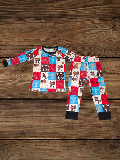 Folded cowboy pajamas kids set with horse print and western bandana patches, warm long-sleeve kids pajama set displayed on wooden background