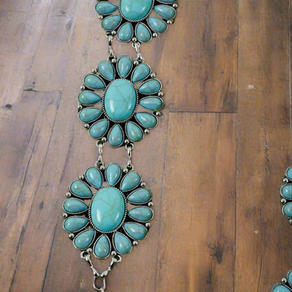 Detailed view of girls’ Western aqua concho belt with turquoise flower patterns on wood.