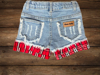 Flat lay of toddler cowgirl denim shorts with red plaid ruffle trim