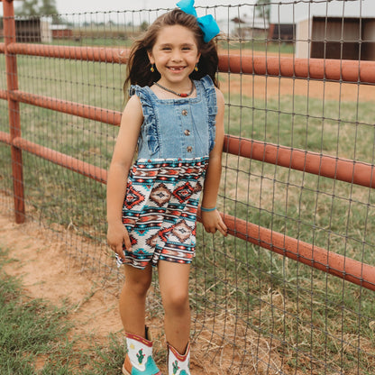 Girl standing by red fence in denim Aztec cowgirl dress