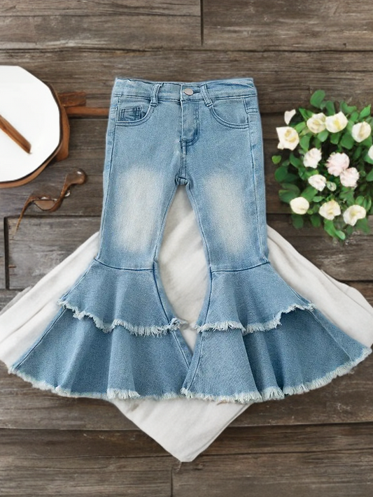 Light blue western bell-bottom pants with double-layer fringe displayed on rustic wooden background.