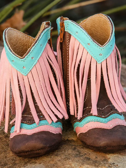 Pink fringe baby leather boots with turquoise trim on hay