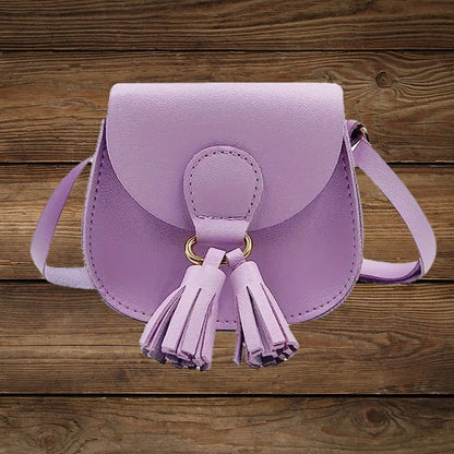 Purple mini crossbody purse with tassel detail on wood background.