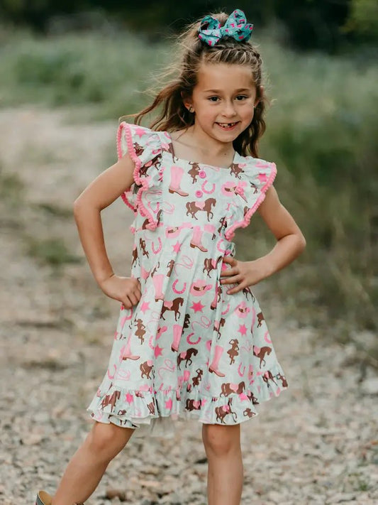 Toddler girl smiling outdoors in teal cowgirl pony print dress
