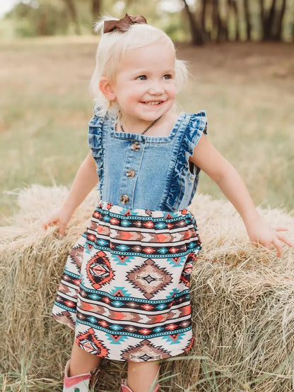 Toddler in denim and Aztec western dress smiling outdoors