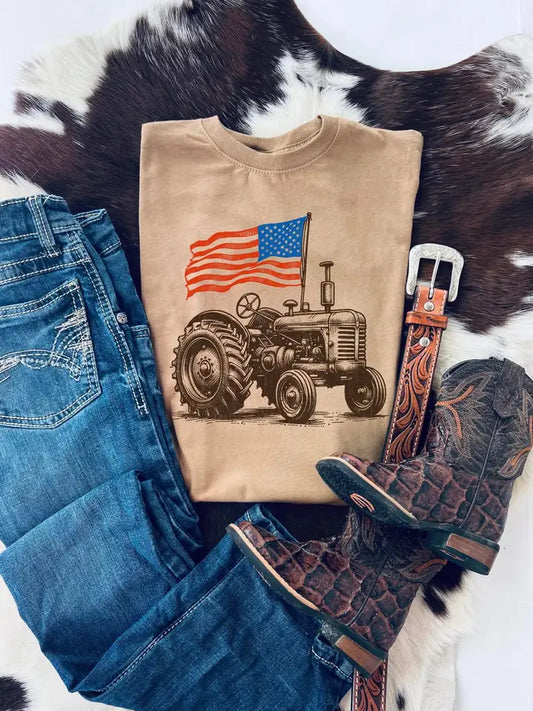 Vintage tractor kids t-shirt with American flag styled with jeans, belt, and cowboy boots on cowhide background.
