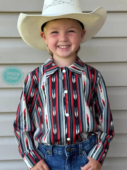 Smiling child wearing Western Roots Kids Long Sleeve Shirt, aztec-inspired button-up in red, black, and white, perfect Aztec Western shirt for kids.